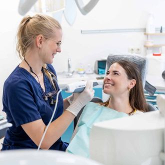 Frau Dr. Völlings führt einen digitalen Zahnabdruck mit einem Intraoralscanner durch. Die Patientin sitzt entspannt im Behandlungsstuhl.