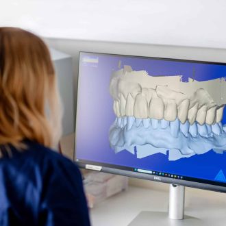 Eine Zahntechnikerin betrachtet am Bildschirm ein 3D-Modell eines Gebisses.