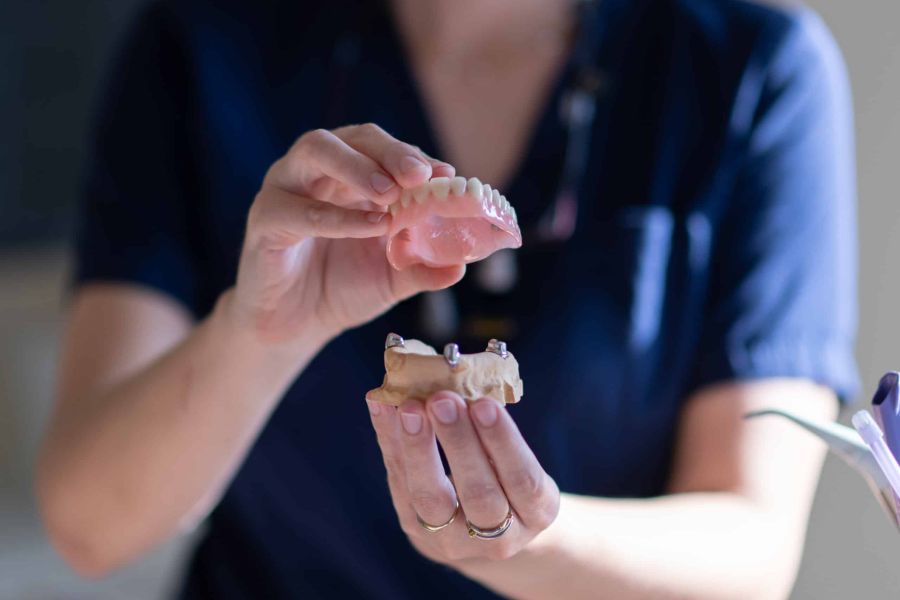 Implantatgetragene Prothese wird gezeigt und ein Zahnmodell mit Implantaten.